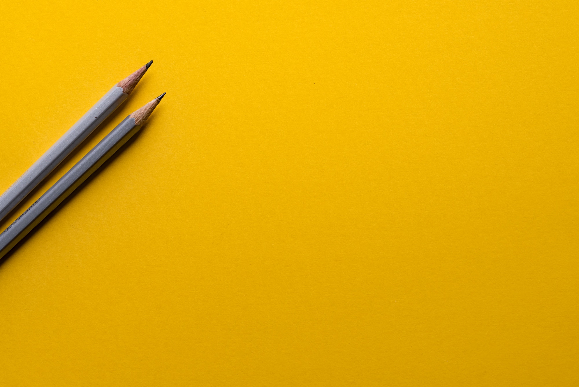 two pencils on a yellow background